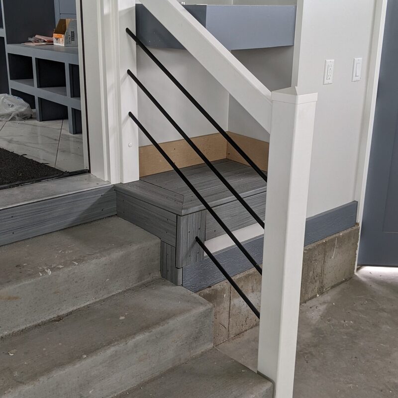 Expand your outdoor living possibilities with this extensive multi-level deck project by DeckPro LLC. This functional retreat seamlessly integrates with the house’s unique stucco and brick architecture, featuring durable, low-maintenance composite decking in a warm brown tone. We installed sophisticated black metal perimeter railings with a safe, traditional baluster design, creating a sturdy and stylish retreat perfect for relaxation or entertaining. Pictured on a beautiful sunny day with distinct railing shadows, this custom build transitions through expansive stairs and is bordered by a stunning natural boulder retaining wall, optimizing panoramic views and creating a truly unique backyard sanctuary.