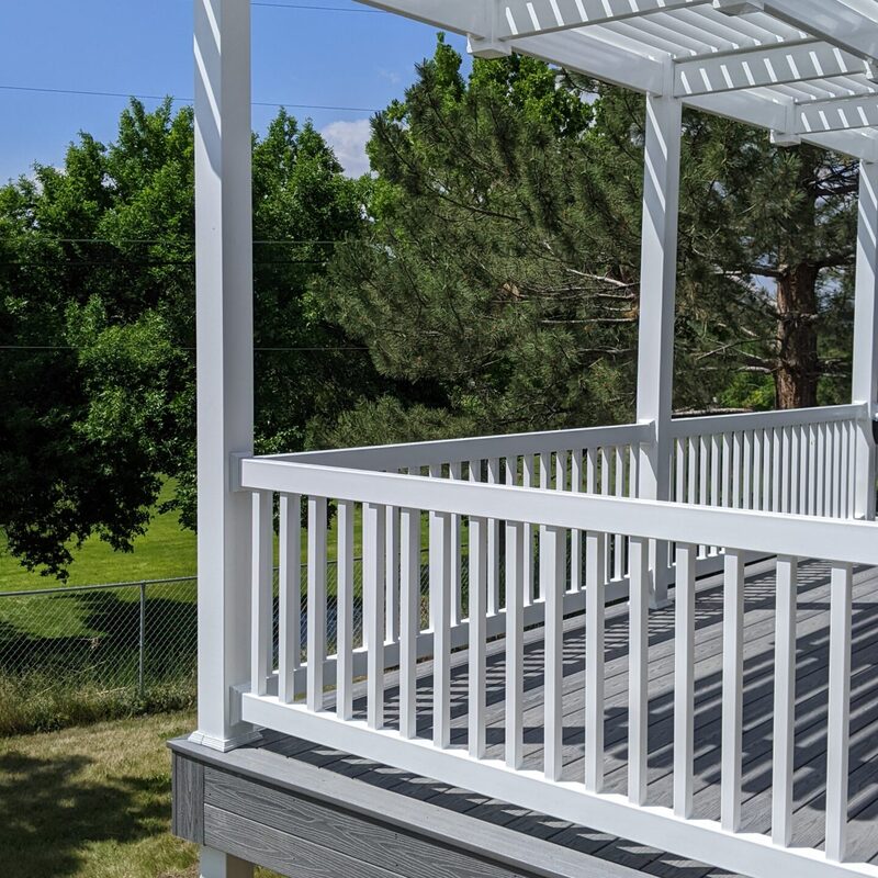Extend your multi-level outdoor living with this dramatic custom raised deck by DeckPro LLC. We took a scenic property bordering natural vegetation and trees and created a unique tranquillity sanctuary perfect for relaxation and large-scale entertaining. Pictured on a beautiful day, this functional retreat features sophisticated, crisp white perimeter railings with vertical balusters to ensure safety without obstructing the expansive, natural views. This sturdy retreat is accessible via comprehensive stairs and a large massive wide set of connecting stairs transition smoothly from raised upper levels to lower patios, defining functional zones perfect for both relaxation and large-scale entertaining. The massive new structure seamlessly connects a raised home to a large grassy yard. Direct access via existing sliding glass doors, multiple conversation areas under covered patio sections, and recessed ceiling lighting for effortless evening use. This build is bordered by large natural boulder rocks on a gravel bed and includes hidden enclosed storage.