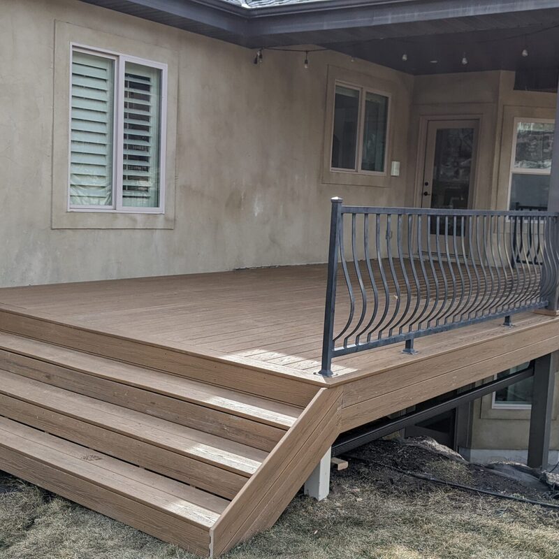 Extend your outdoor living possibilities with this custom deck by DeckPro LLC, which combines rustic elements with modern materials. We installed low-maintenance composite decking in a warm brown tone and paired it with a unique railing system that features natural wood posts and integrated wire mesh infill panels. For the ultimate in functional design, we included extensive built-in L-shaped bench seating, creating a cozy and inviting perimeter perfect for taking in scenic views.