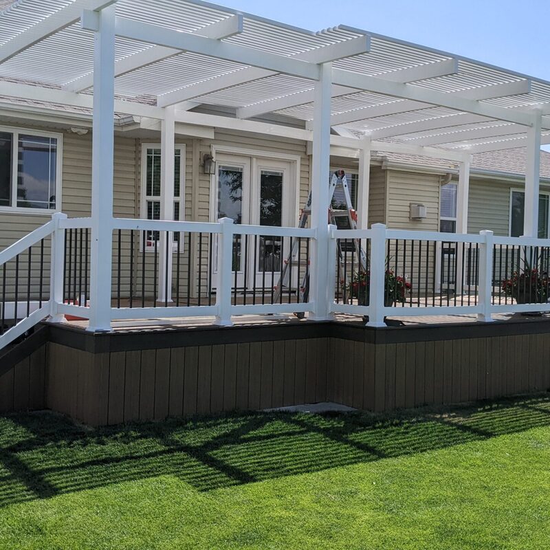 Extend your multi-level outdoor living with this expansive composite deck by DeckPro LLC. We installed high-quality, low-maintenance composite decking and paired it with safe and sophisticated black perimeter railings to ensure safety without obstructing views. Pictured on a beautiful partly cloudy day, the structure transitions via dramatic, massive, wide staircases to a stamped concrete lower level. Defining functional areas with comprehensive stairs and large potted plants, this sturdy retreat maximizes multi-directional natural views for a unique tranquillity sanctuary. Direct access is available via multiple existing sliding glass doors, while recessed lights in the under-deck ceiling allow for effortless evening use.
