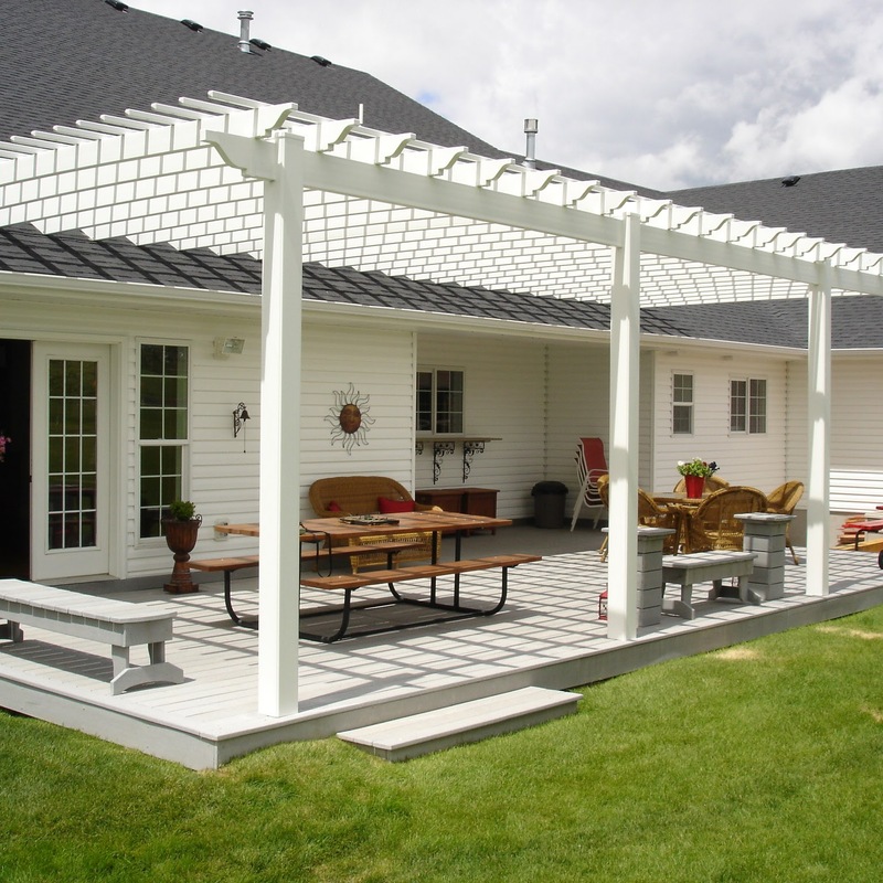 Extend your multi-level outdoor living with this massive custom composite deck and pergola transformation by DeckPro LLC. This functional retreat seamlessness connects a multi-story home with rough grading and rough landscaping, pictured bordering natural vegetation and a dirt road construction area trailing trailing Leading to spectacularly multi-directional natural views. Pictured on a beautiful day, this dramatic structure features extensive gray composite planks paired with sleek black vertical perimeter railings and safe, sturdy natural timber timber framing border define zones complete with custom unique rustic timber framing and continuous perimeter railing.