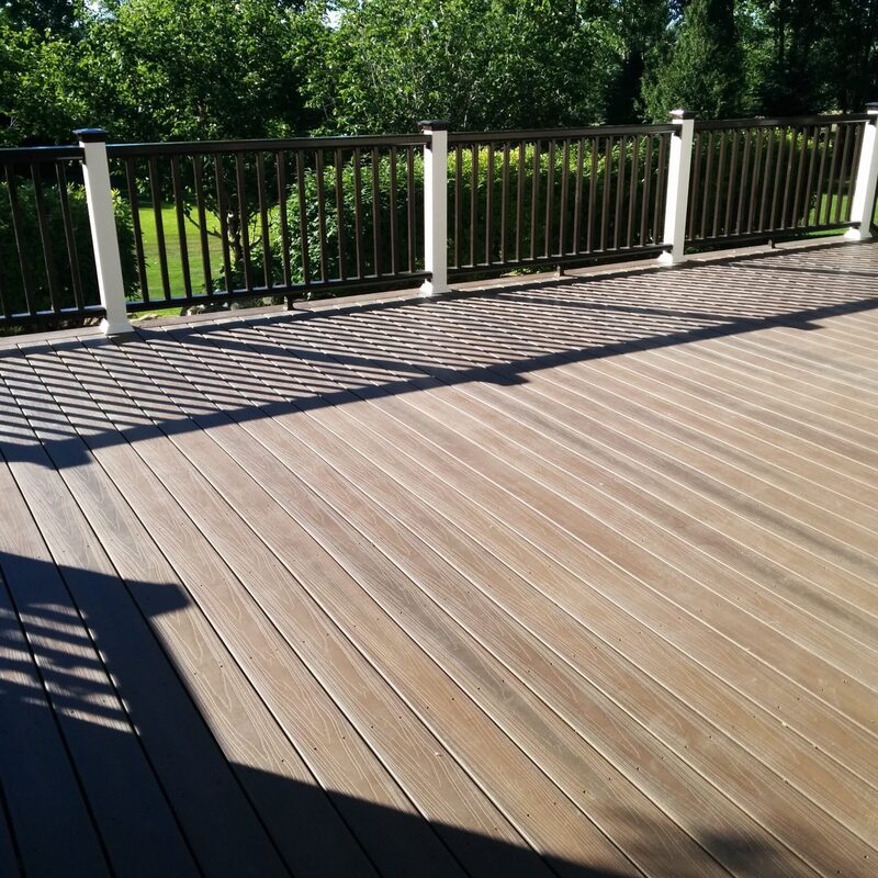 Expand your outdoor living possibilities with this custom deck by DeckPro LLC, which combines rustic elements with modern materials. We installed low-maintenance composite decking in a warm brown tone and paired it with a unique railing system that features natural wood posts and integrated wire mesh infill panels. For the ultimate in functional design, we included extensive built-in L-shaped bench seating, creating a cozy and inviting perimeter perfect for taking in scenic views.