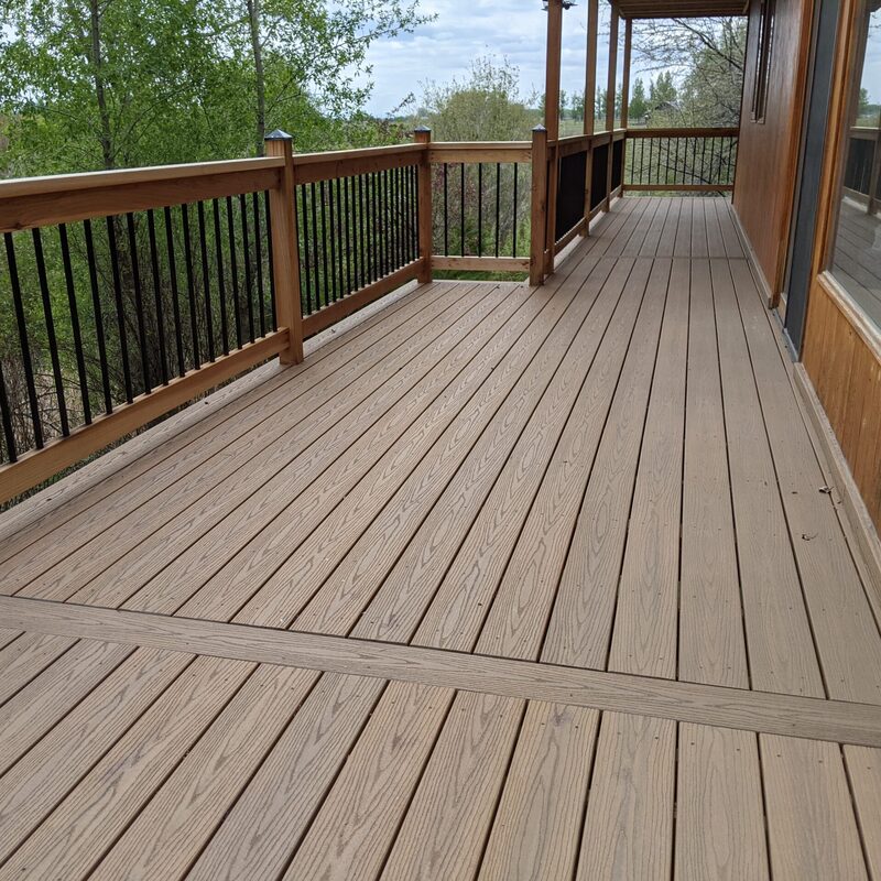Extend your outdoor living possibilities with this custom raised deck by DeckPro LLC, which beautifully balances rustic elements with modern materials. We installed low-maintenance composite decking in a warm brown tone and paired it with a unique railing system that features natural wood posts, top rails, and horizontal wire mesh panels for unobstructed views. For the ultimate in functional design, we included extensive built-in L-shaped bench seating, creating a cozy and inviting retreat perfect for relaxing and taking in scenic mountain views.