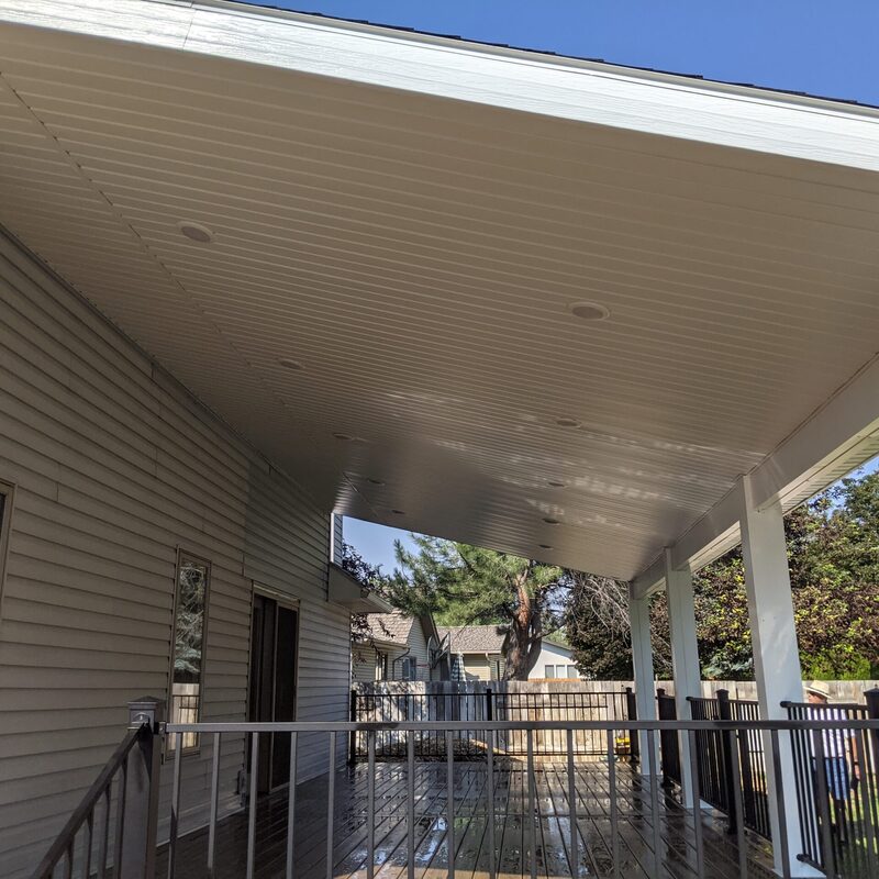 Extend your spectacular multi-directional natural views with this rustic custom composite deck by DeckPro LLC. Pictured bordering natural vegetation and a dirt road/trail on a beautiful partly cloudy day, this sturdy retreat features rich brown wood-grain composite decking with a defined clean picture frame board pattern around the perimeter. This sturdy retreat borders construction work featuring multi-directional natural views of panoramic mountains and a lake.