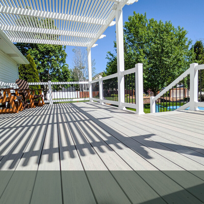 Light Grey Composite Deck with Custom White Slatted Pergola This stunning on-deck perspective showcases a recent outdoor living transformation by DeckPro LLC. The project features premium light grey composite decking that provides a sleek, modern, and low-maintenance foundation. Overhead, a custom-built white slatted pergola extends from the home, casting beautiful, clean geometric shadows across the deck surface while providing the perfect balance of sun and shade. The space is safely enclosed by DeckPro's popular two-tone railing system, combining classic white vinyl with modern black metal balusters.
