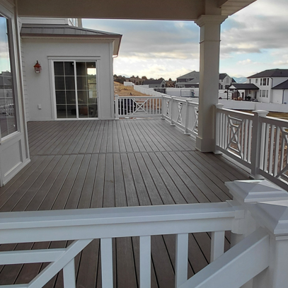 An expansive covered deck featuring a high-end vinyl railing installation by DeckPro LLC in Idaho Falls, ID. This view highlights the clean integration of white vinyl railings with a wood-look ceiling and dark composite decking.