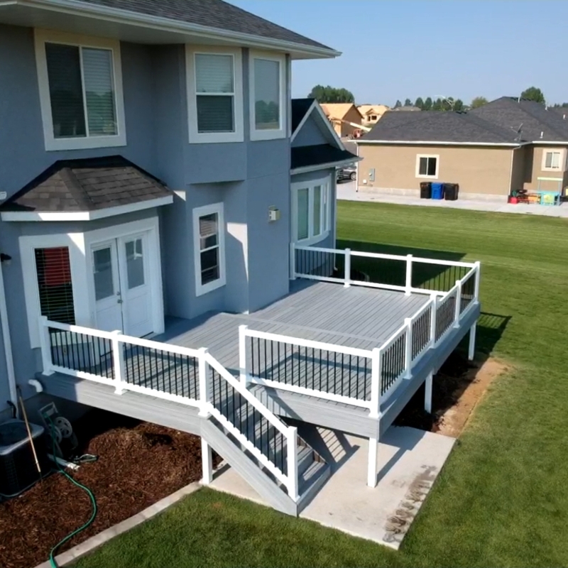 Expand your outdoor living possibilities with this extensive multi-level deck project by DeckPro LLC. This custom raised structure transitions seamlessly into a lower-level covered lounge area, offering the perfect blend of sun and shade. We installed high-quality, low-maintenance composite decking in a warm brown tone and paired it with sophisticated black metal perimeter railings and wide, inviting stairs. Pictured on a beautiful day, the build showcases clean white support posts and a partial under-deck ceiling, creating a sturdy and stylish retreat perfect for relaxation or large-scale entertaining.
