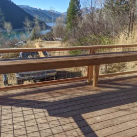 deck and bench with mountains and stream in background.