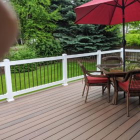 charming brown deck in lush green back yard.